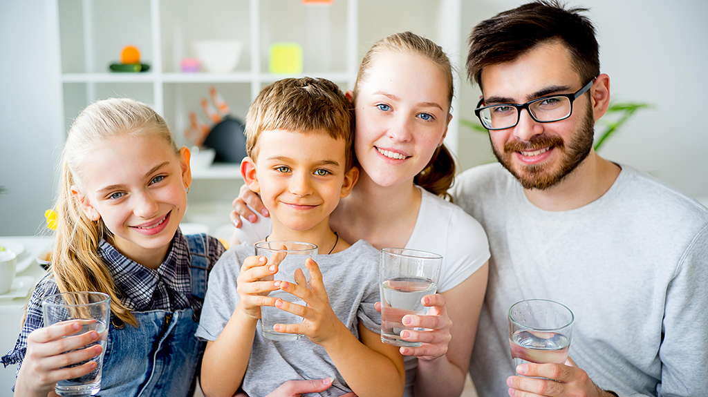 Smiling family members holding glasses of clean drinking water