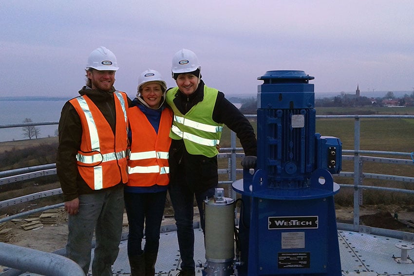 Three plant operators standing near a WesTech drive on a customer site