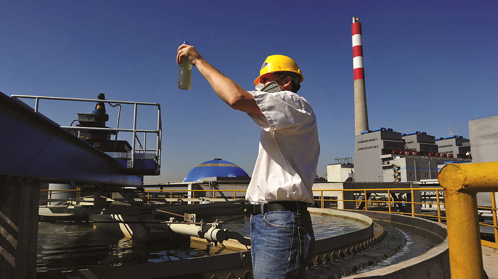 A WesTech field engineer standing in front of a clarifier inspects a water sample