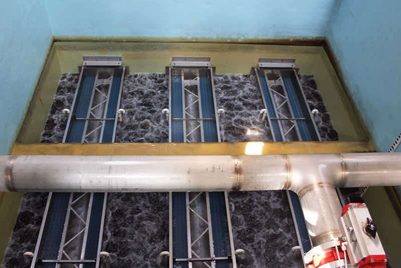 A downward view into a rectangular concrete filter cell containing three rectangular MULTIWASH wash troughs above the cell’s turbulent water.